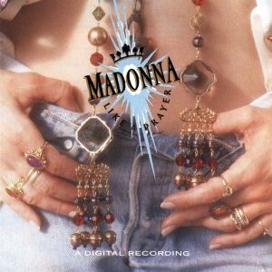 The cover of Madonna's 1989 album Like a Prayer. It's a photo of a woman's bare midriff and her hands, with many rings on her fingers, hooked into the waistband of her jeans. A chain of different types of beads separates in two and dangles in front of her midriff. Madonna's name and the album title are printed and positioned over the woman's belly button.