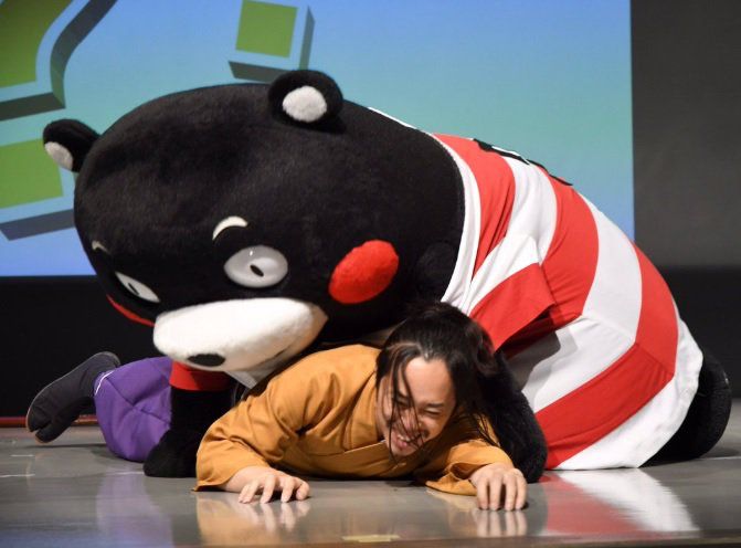 Kumamon wrestling/consuming the flesh of a person while wearing a red and white striped singlet? Shirt? Something with big red and white horizontal stripes.