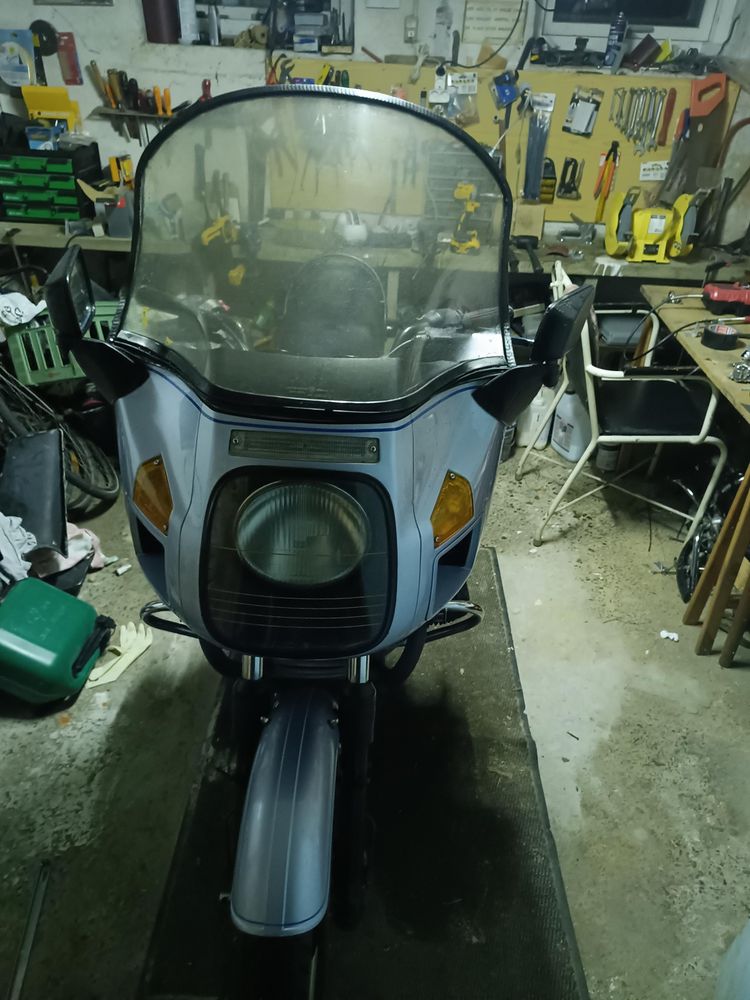 Large blue BMW r100 parked in messy garage