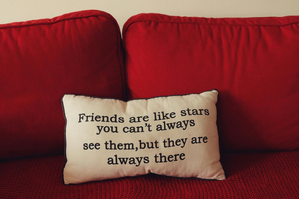 Graphic: A White pillow on a red couch. There's an inscription on the pillow: Friends are like stars. You can't always see them, but they are always there.