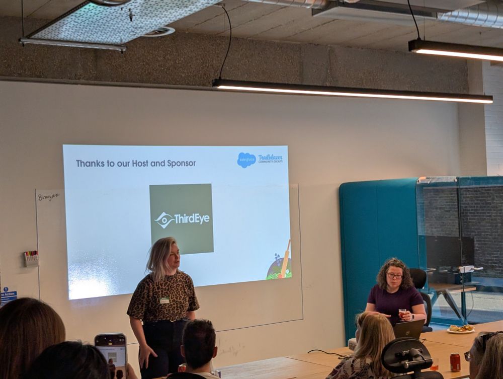 A speaker addresses the audience in front of a projected slide that reads "Thanks to our Host and Sponsor" with the ThirdEye logo beneath it. Another woman sits nearby with a drink and plate of food. The atmosphere is casual and collaborative.