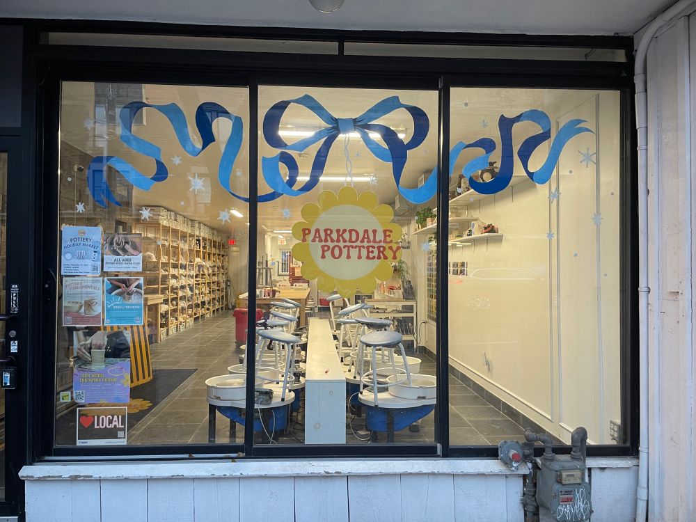 The pottery studio has large front windows with the logo in the middle. I painted a blue ribbon bow in the top middle that curls around the tops of the other windows with little snowflakes around. 