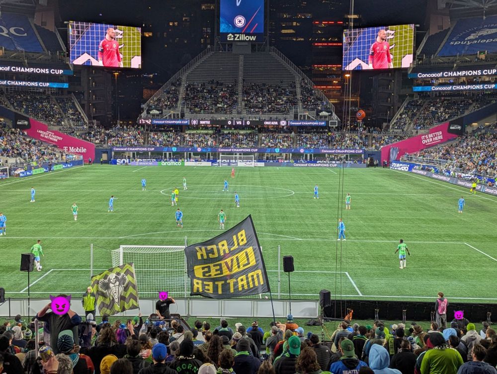 Royal Brougham Park showing the ECS supporter section with a large "Black Lives Matter" flag waving while the Sounders play 