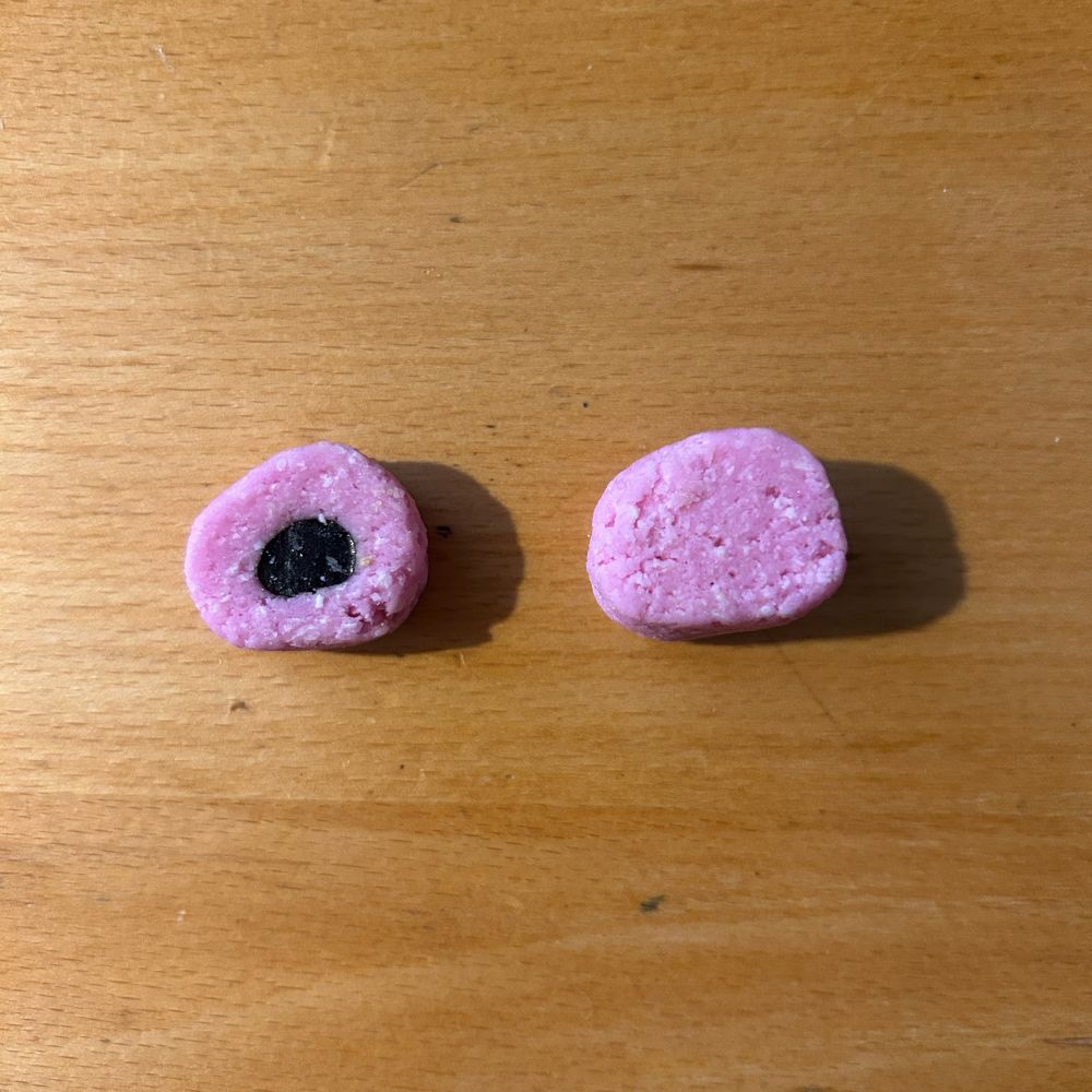 Two pink coconut liquorice allsorts, one which has liquorice in the centre, one which is all coconut