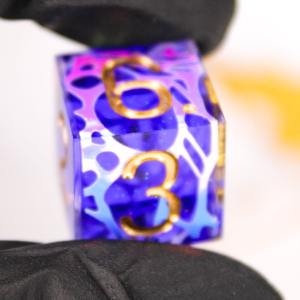 A purple d6 with iridescent patterns and gold numbers.