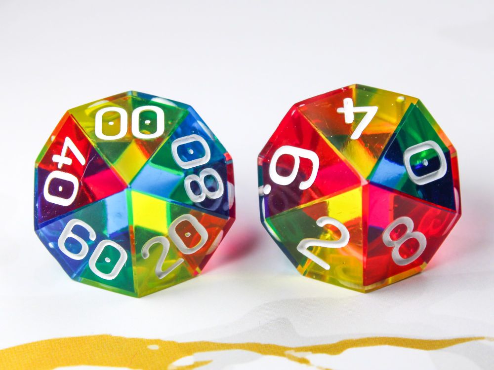 A photograph of two 10 sided dice. Each side is coloured either cyan, magenta or yellow which combine into a full rainbow spectrum of colour.