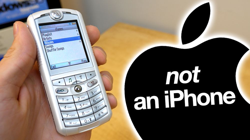 a YouTube thumbnail featuring the Motorola ROKR (or "iTunes Phone") being held above a wooden table. On the phone's screen is the iTunes player. To the right of the phone is an Apple logo, with text on it that reads "not an iPhone."