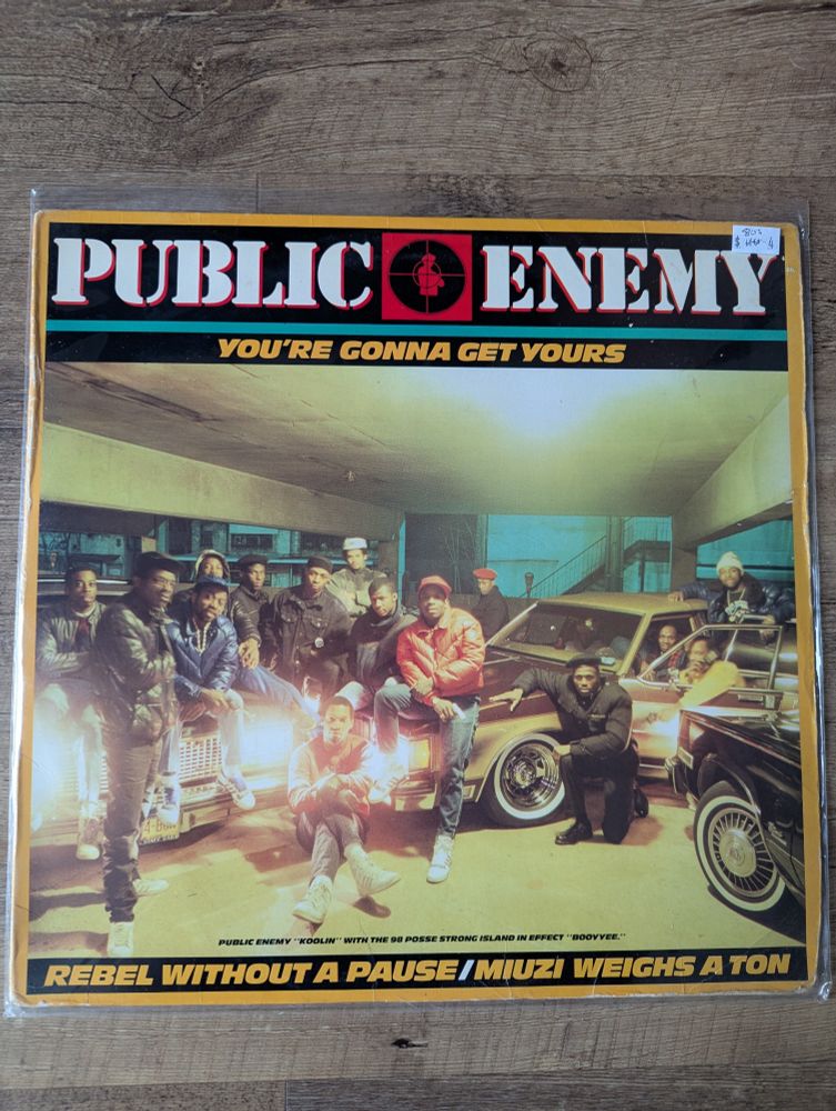Front sleeve for Public Enemy vinyl "You're Gonna Get Yours." Features a bunch of dudes looking cool as hell posing by cars in a parking garage