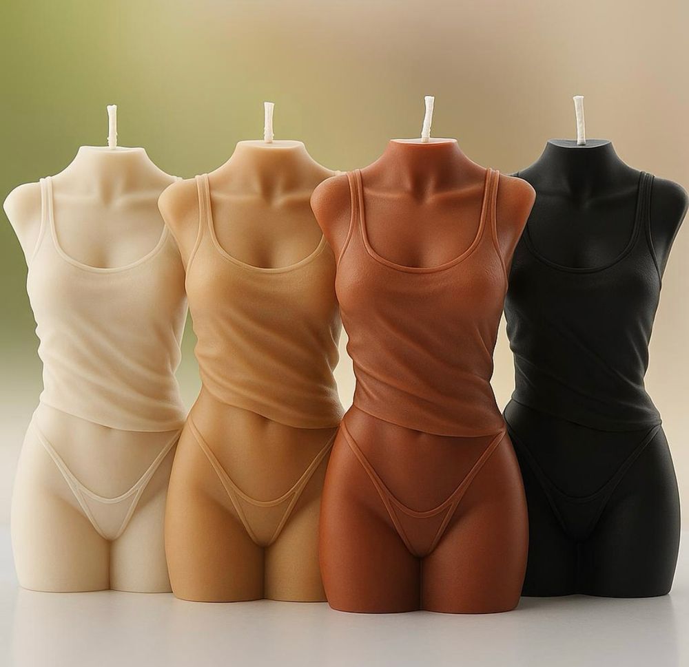 Four headless figure candles of women in underwear ranging in colour from cream to black 
