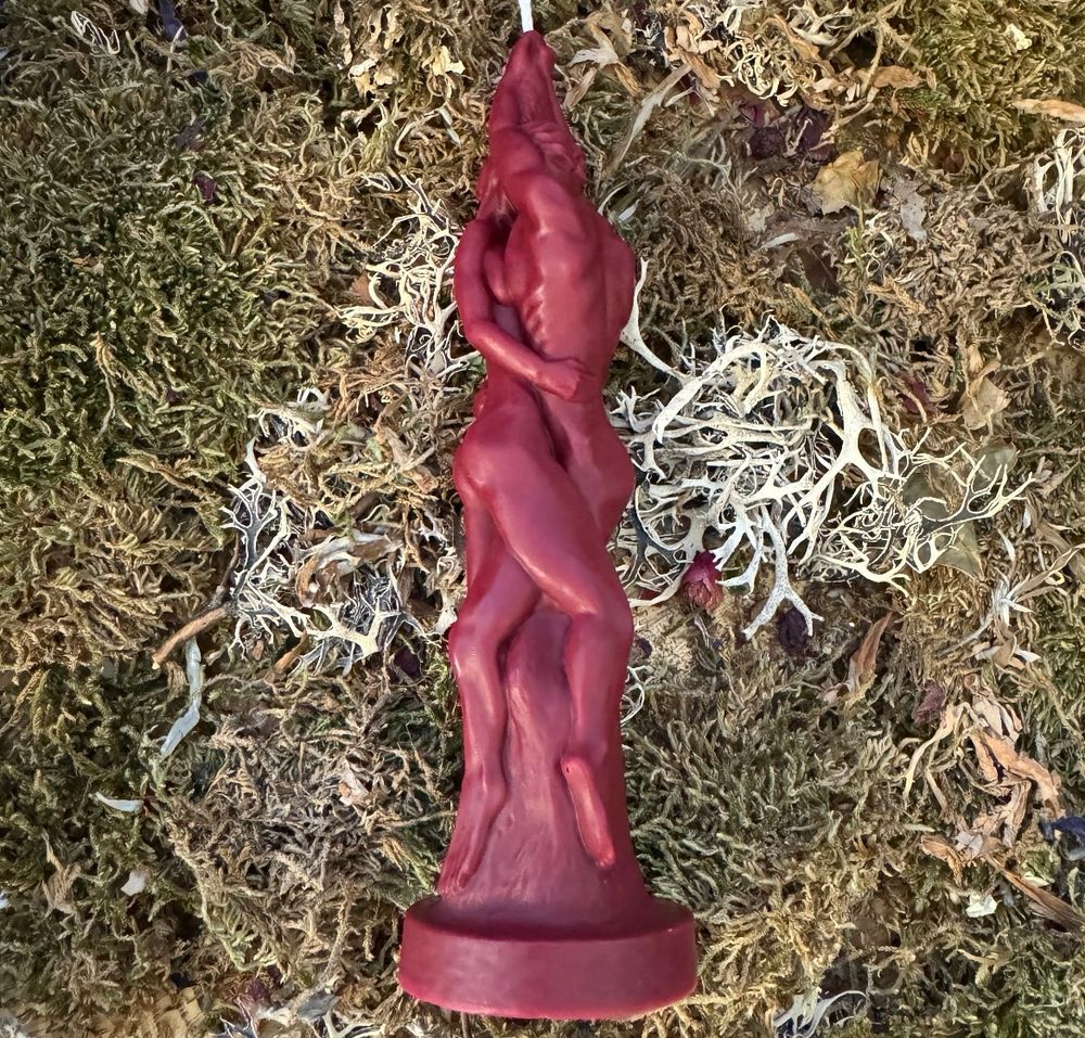 A red figure candle of two people with their naked bodies entwined on a bed of some kind of moss stuff