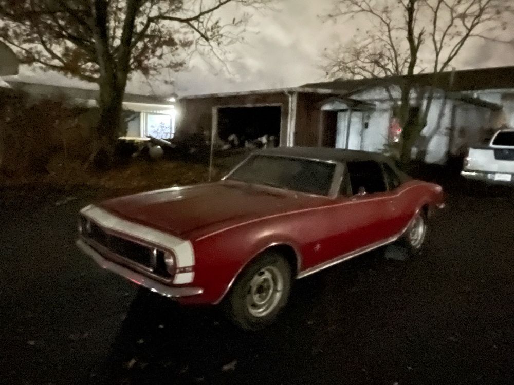 A red 1967 Camaro sitting in a driveway