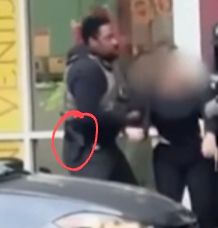 A zoomed in still shot of the recording in which a holstered gun can be seen at the hip of one of the ice agents. The gun has been circled in red.