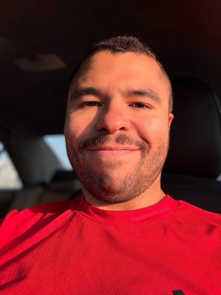 A guy wearing a red shirt sitting in his car