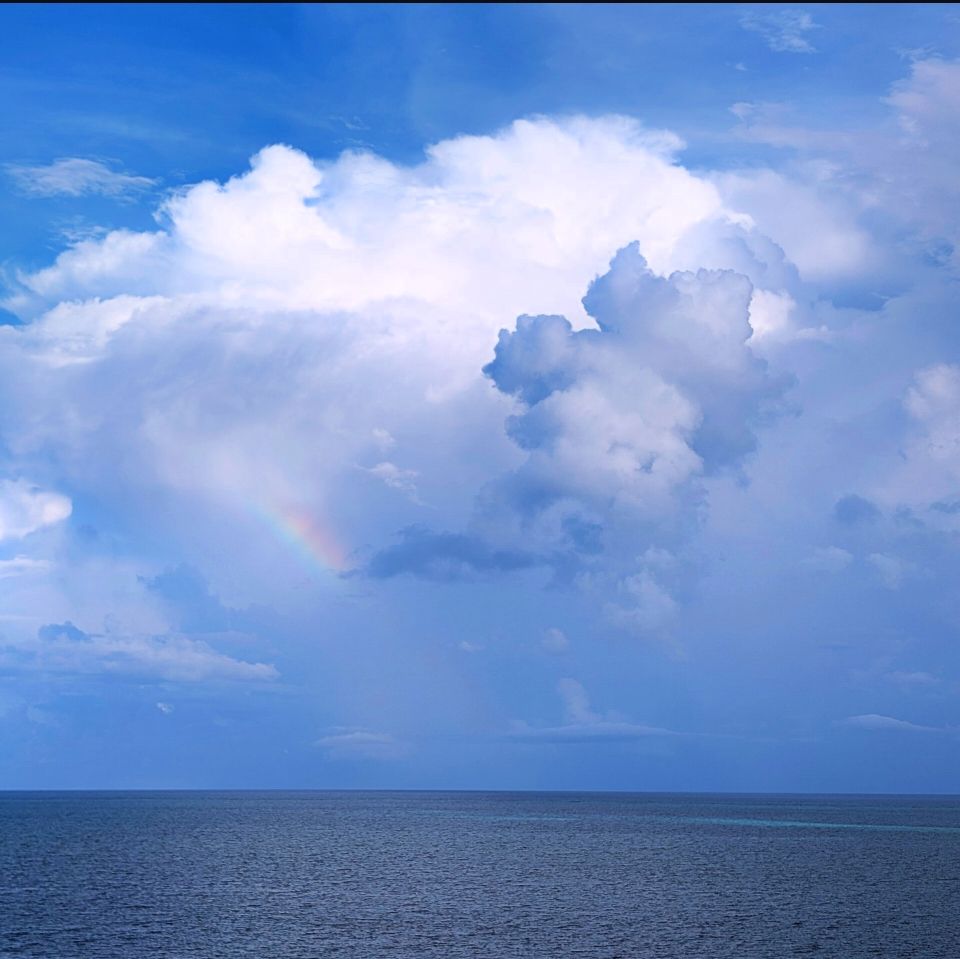 Big, puffy, and slightly dark clouds. On the left there's a small rainbow in the clouds.
