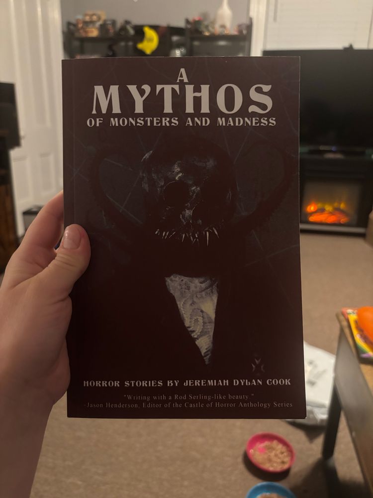 White woman’s hand holds a copy of A Mythos of Monsters and Madness by Jeremiah Dylan Cook