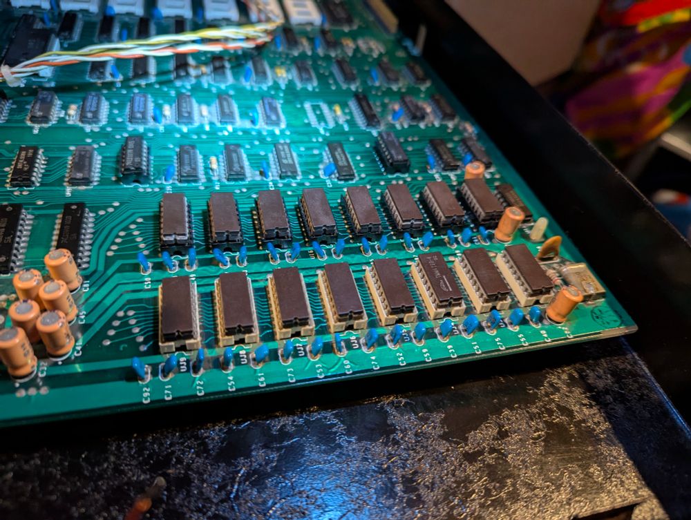 A picture of the front section of the commodore pet motherboard. The front row of eight RAM chips are the original white sockets. The second row, behind the first, are lower profile and black plastic.