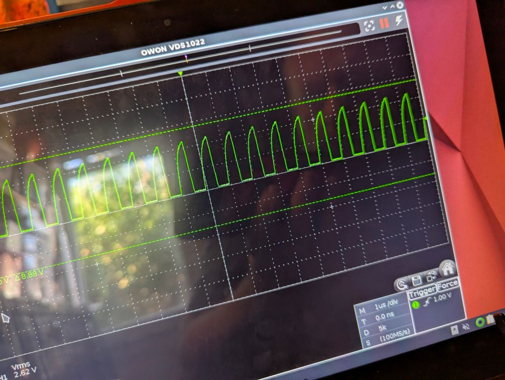 A picture of an oscilloscope display showing a regular repeating wave. There is a distinct gap between each rising wave.