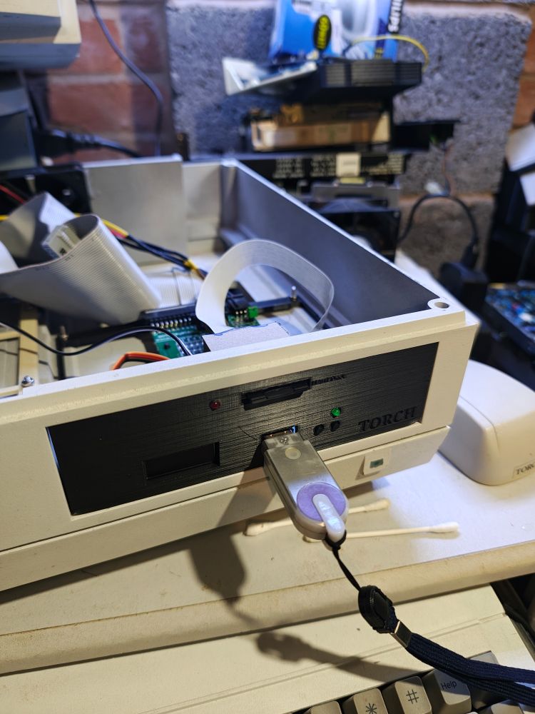 The front of the Torch Triple X with the lid removed. An SD card is stuck into the top of the floppy drive panel and a grey usb stick is inserted underneath into the Gotek.
