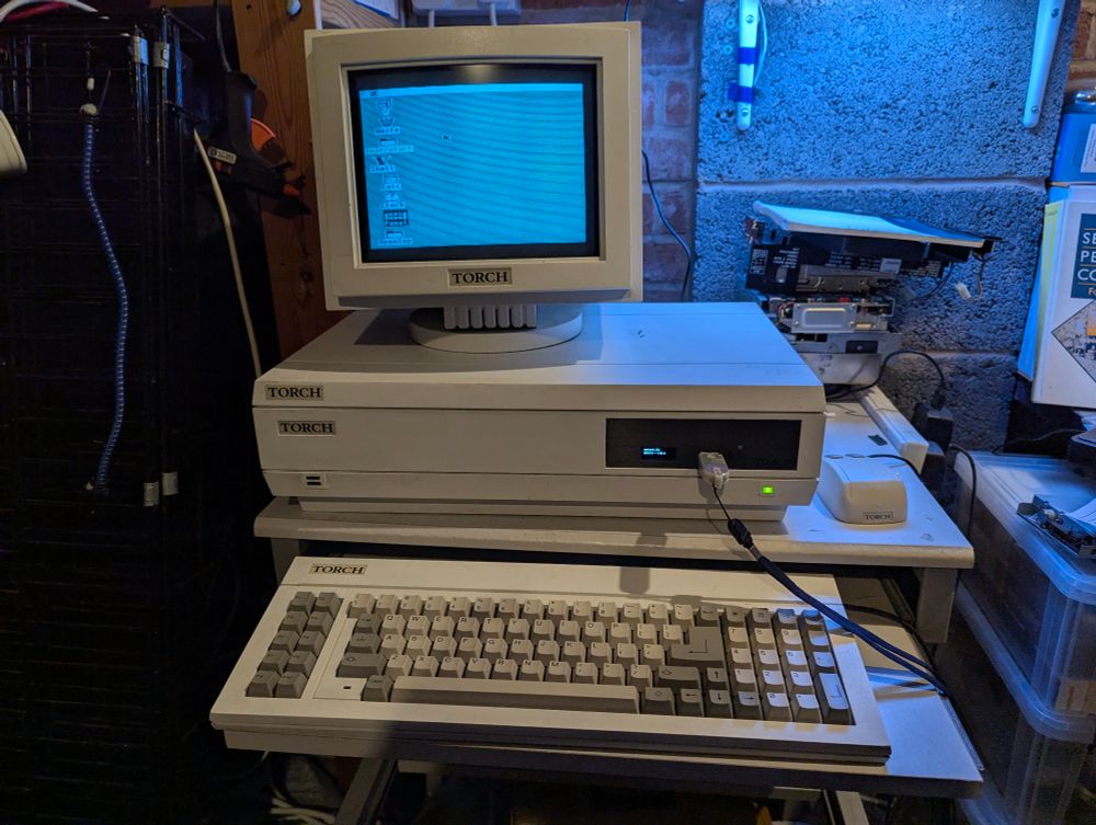 A picture of the Torch Triple X in its case with Gotek floppy drive and small Sony monitor. The OpenTop desktop is displayed but everything is in low resolution for no explicable reason...