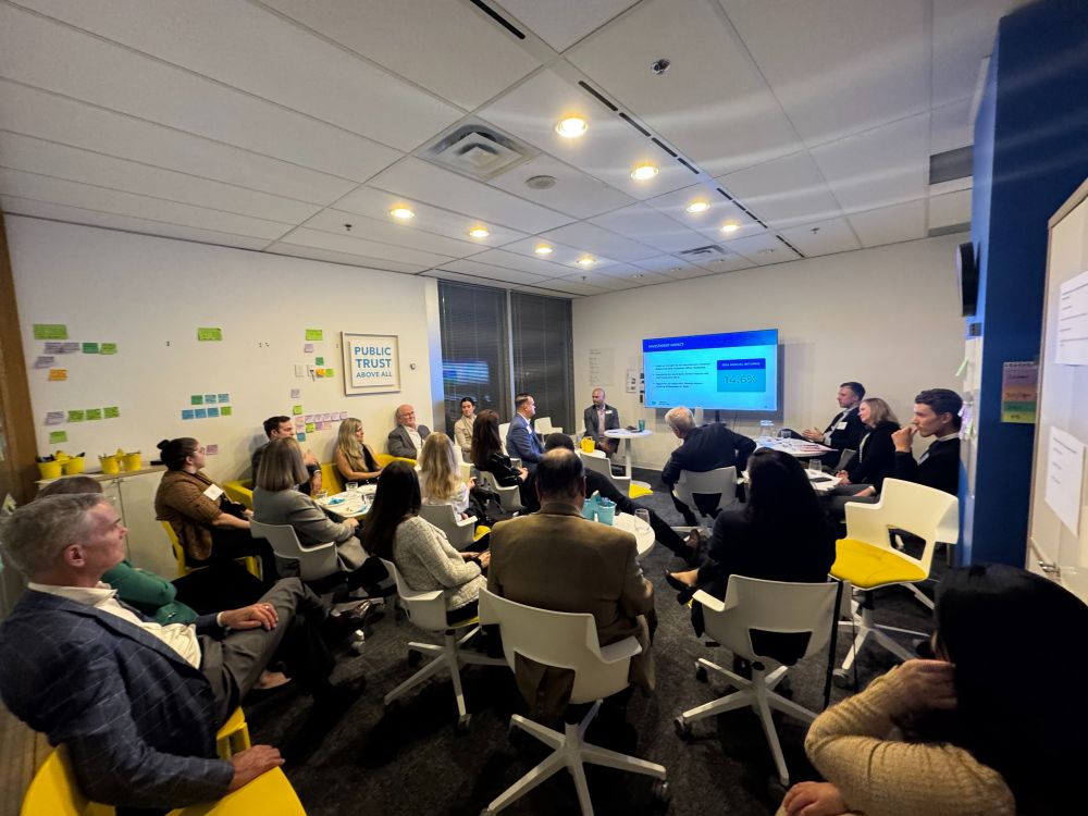 Group of people sitting in a room facing a presentation on a screen.