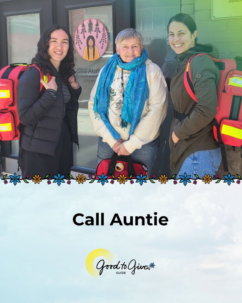 Photo of three people posing for a photo. They are all carrying red medical backpacks. Call Auntie’s logo can be seen behind them on the door of the building. Call Auntie. Good to Give Guide logo.  