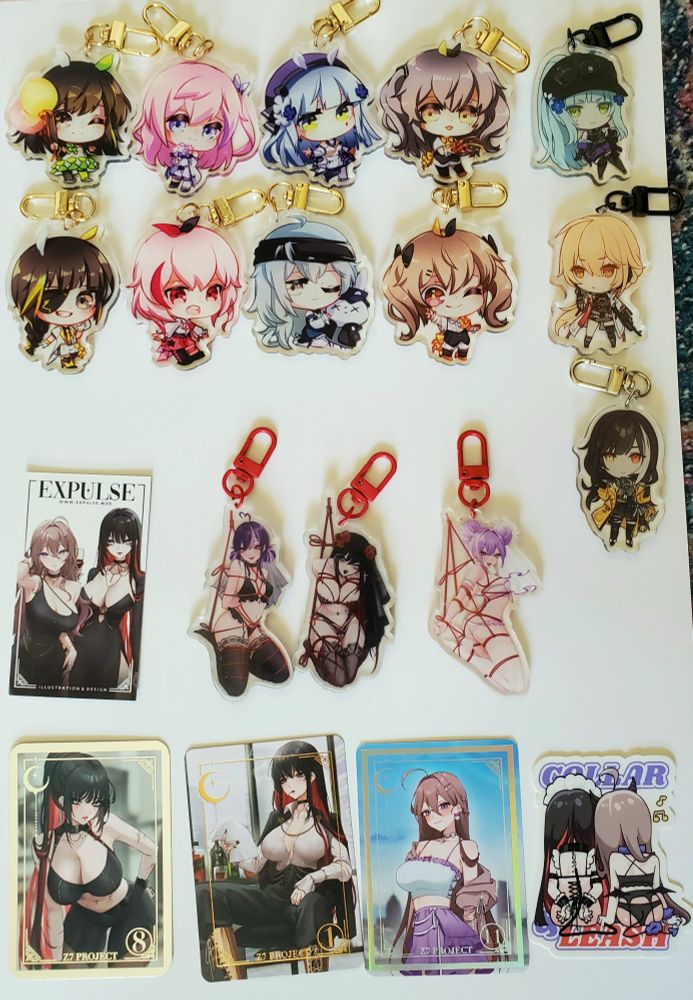 8 GFL1 charms by @ebbilin.bsky.social. 3 GFL1/2 charms by @teru.moe. Bondage charms + cards + sticker by @expulse.bsky.social. 

If you read this you'll know that ebbilin is the only artist this AX who I've bought stuff from previously, way back at my 1st AX in 2017 before I stopped attending after Covid struck. Their Walkure groupshot + solo Freyja and Mikumo prints are still hanging on my wall today.