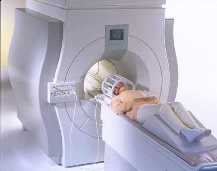 person laying on a bed in an mri machin wearing a head cage
