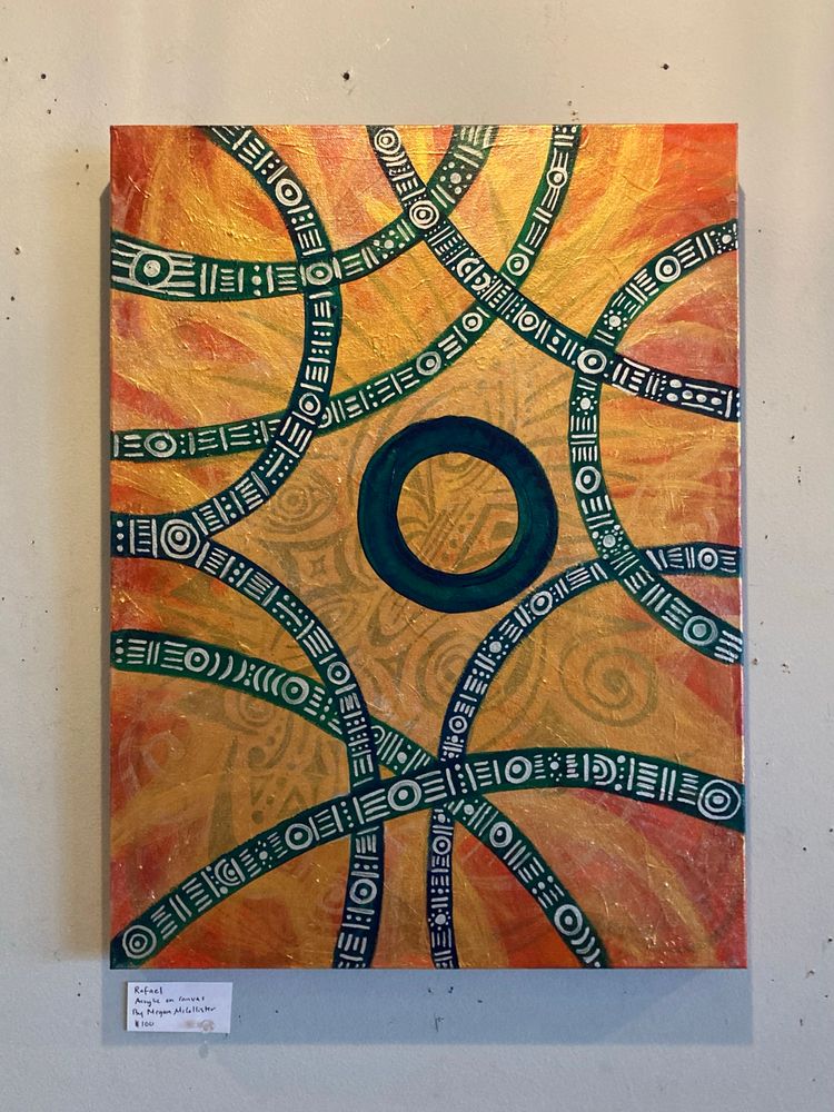 Raphael, acrylic on canvas, by Megan McCollister, an artist based in Lincoln, Nebraska. The painting is perhaps a biblically accurate depiction of the generally non-canon archangel, represented here by a thick black circle set against an orange- and red-tinged background of implied flames, through which can be seen various abstract mystical symbols in gray. Surrounding the circle are black arcs, all bending toward and away from the circle in non-uniform directions, and adorned with symbols painted in white: concentric circles, short lines, arcs, and dots distributed in repeating patterns along their lengths. The work is mounted on a plain gray wall. There is a small label card with the title, medium, artist name, and sale price ($100).