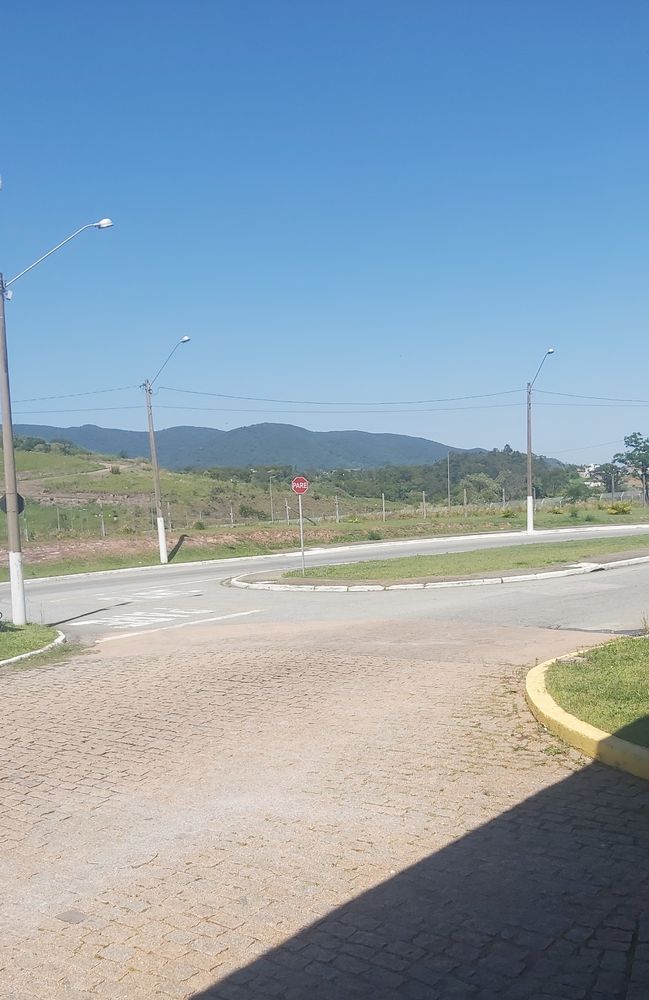 Vista de uma plataforma de onibus, rua ao fundo e uma montanha ao longe
