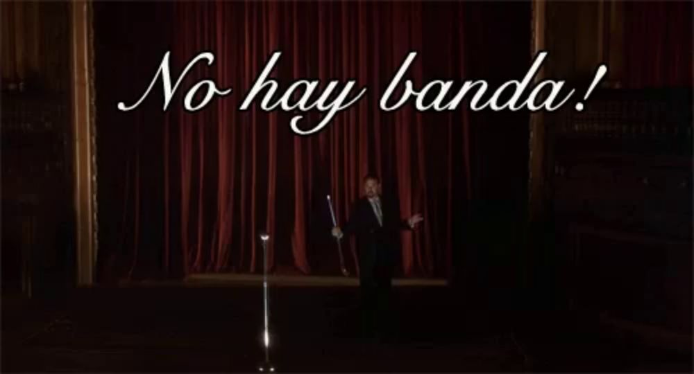 a man singing into a microphone on a stage with the words no hay banda written above him