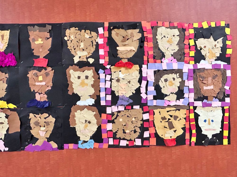 Zoomed in on the artwork. A school hallway bulletin board with student self portrait artwork on it