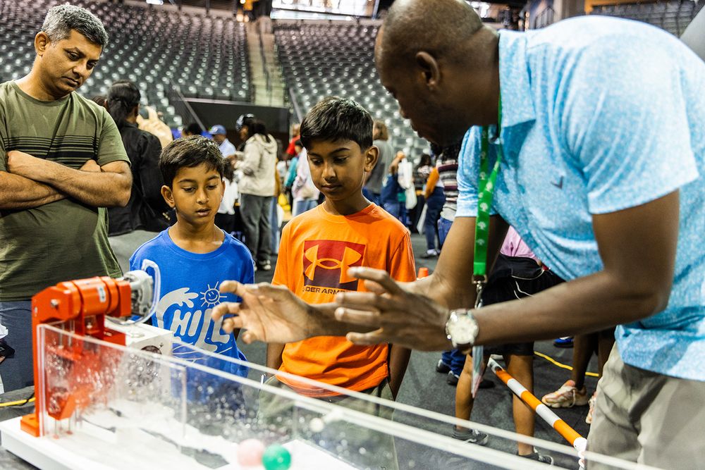 A volunteer explains wave energy to kids at STEM Fest.