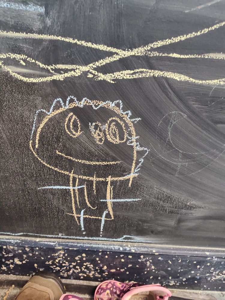 Children's chalk drawing of a person with large head and sticks for limbs