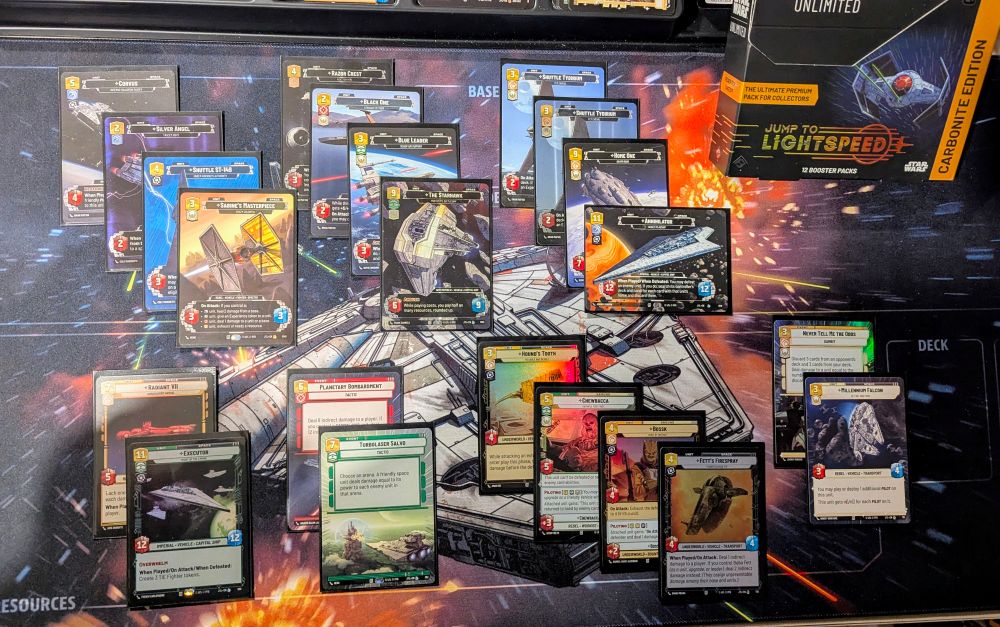 A tabletop view of Star Wars Unlimited cards, a sci-fi themed playmat, and a JUMP TO LIGHTSPEED CARBONITE EDITION' booster pack box.