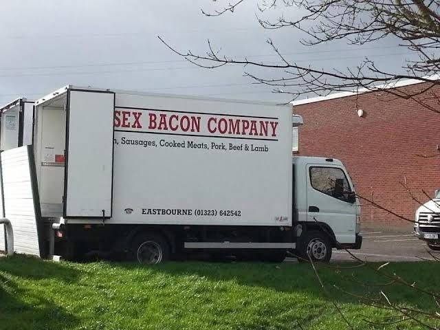 A white trailer truck with its back door covering part of the company name so it says “Sex Bacon Company” in big red letters.