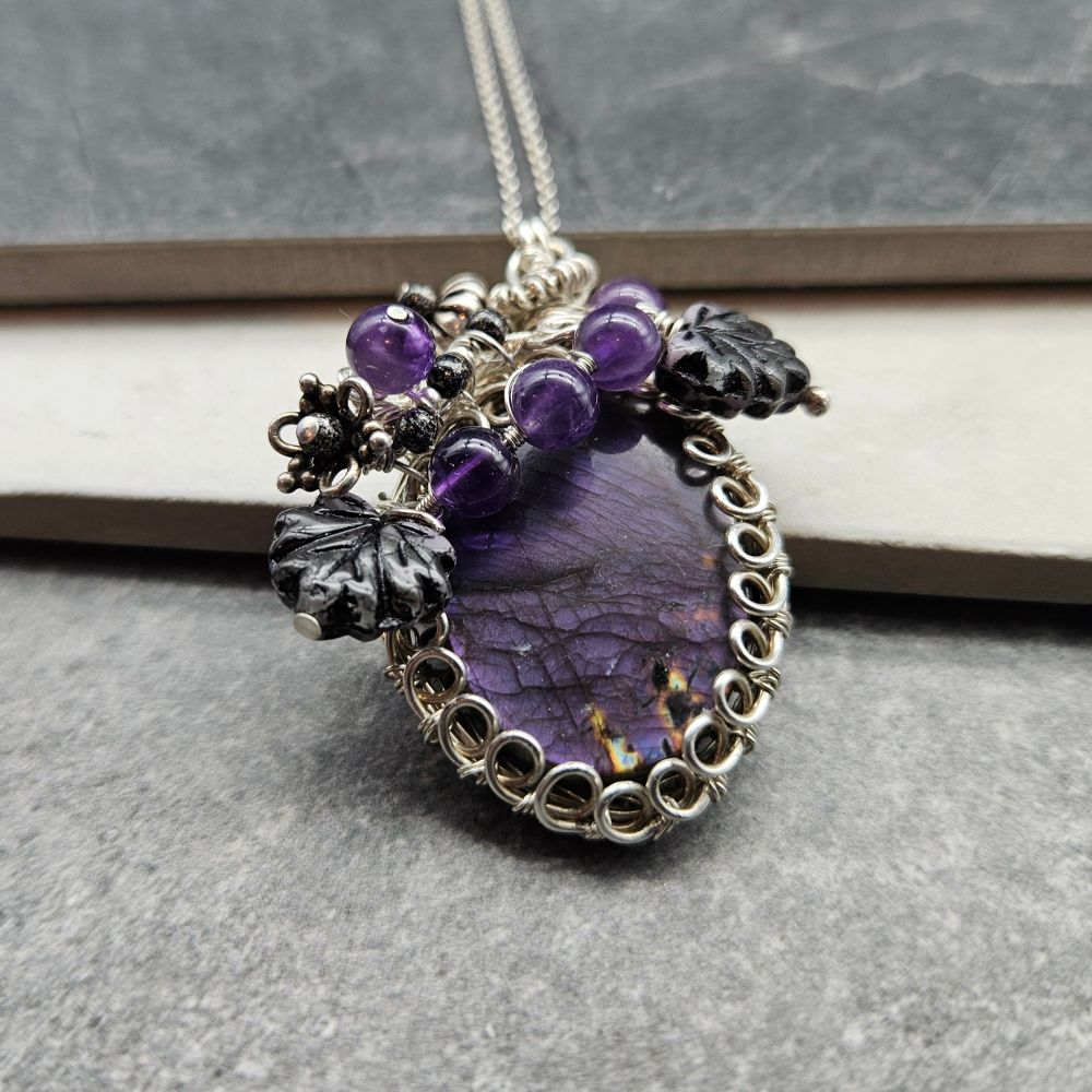 A hand wrapped purple labradorite wrapped in sterling, amethyst, and Czech leaves.