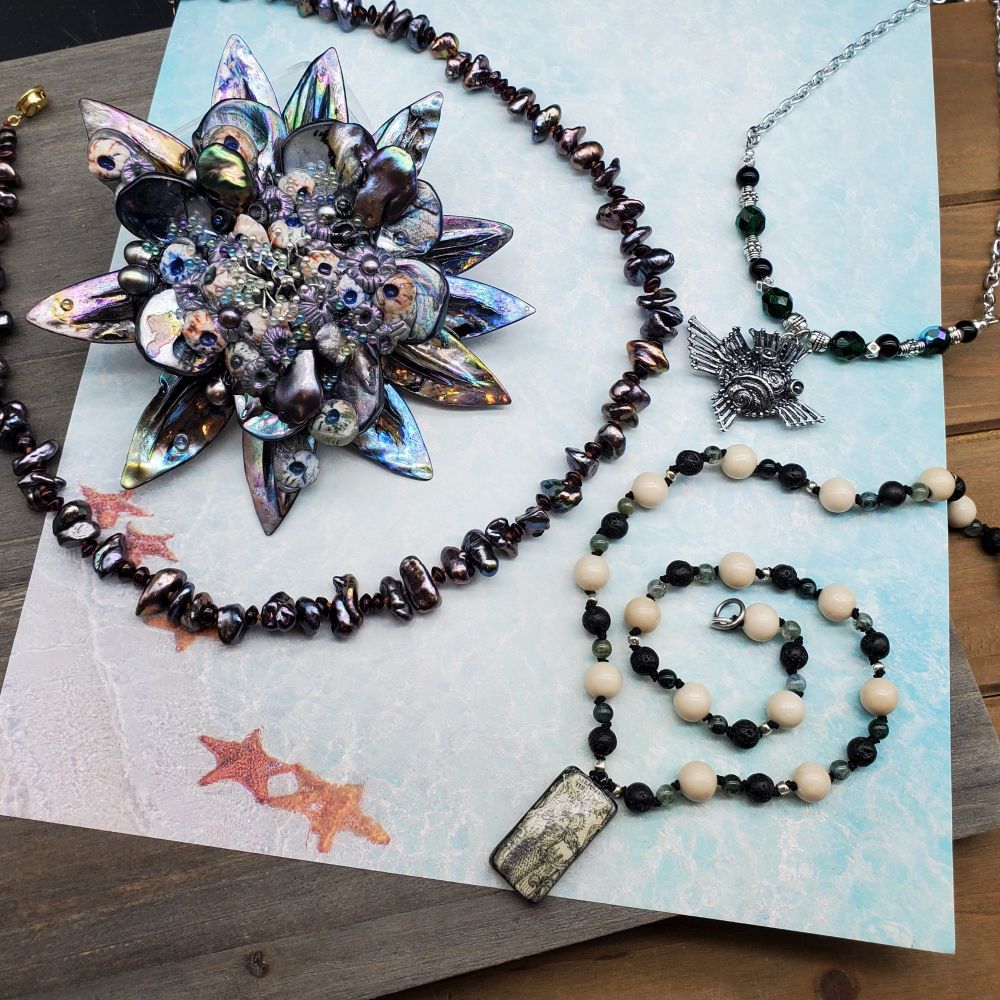A big barnacle brooch, a knotted necklace with a Shakespearean focal, a dark pearl strand, a funny blowfish necklace.
