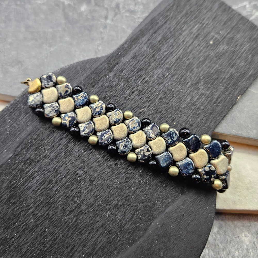 An all gender bracelet in muted gold and black ginkos. 
