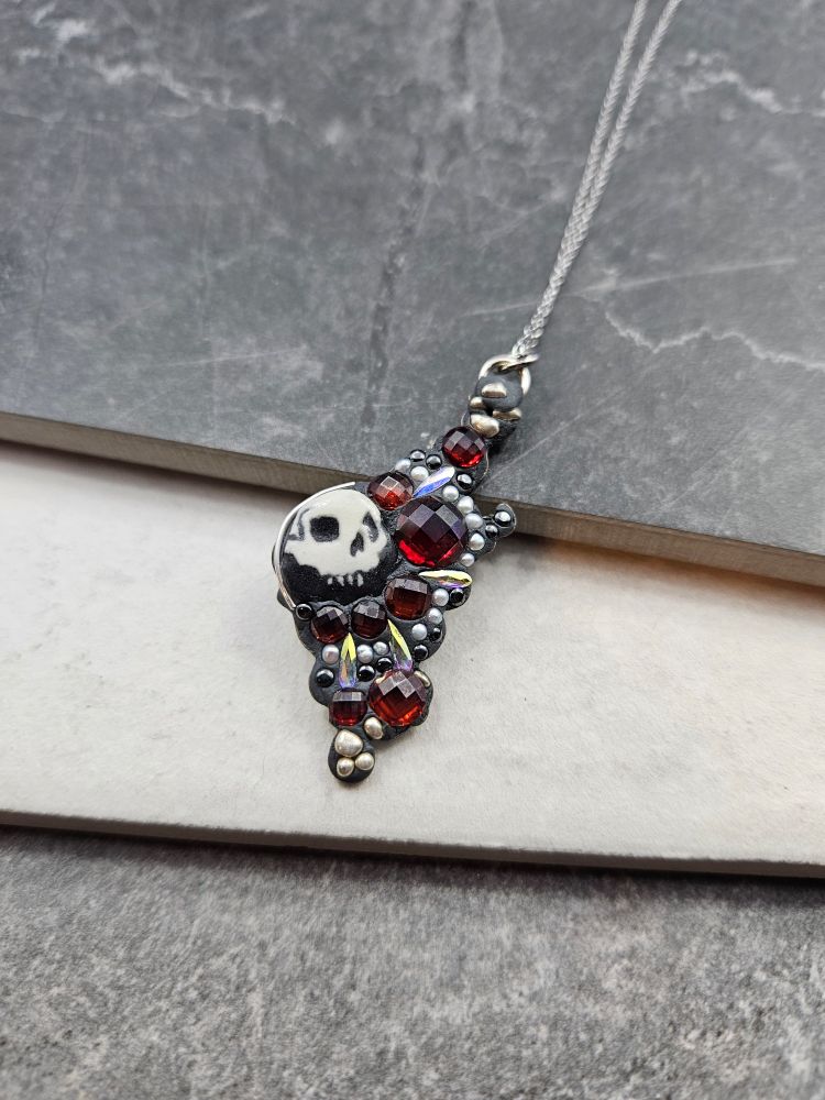 A mosaic on clay with skulls and red gemstones.