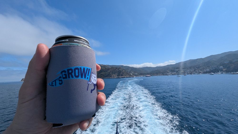 Beer in a Let's Grow koozie. Catalina Island is in the background asking with a boat's wake