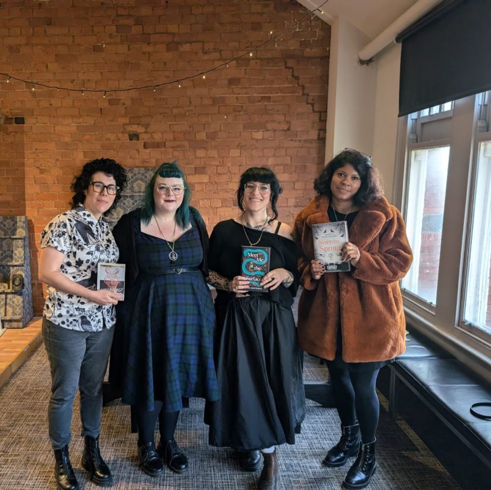 Meg Ripley, Kibrina, Jodie Matthews and Olivia Isaac-Henry standing next to each other and holding up their books. 