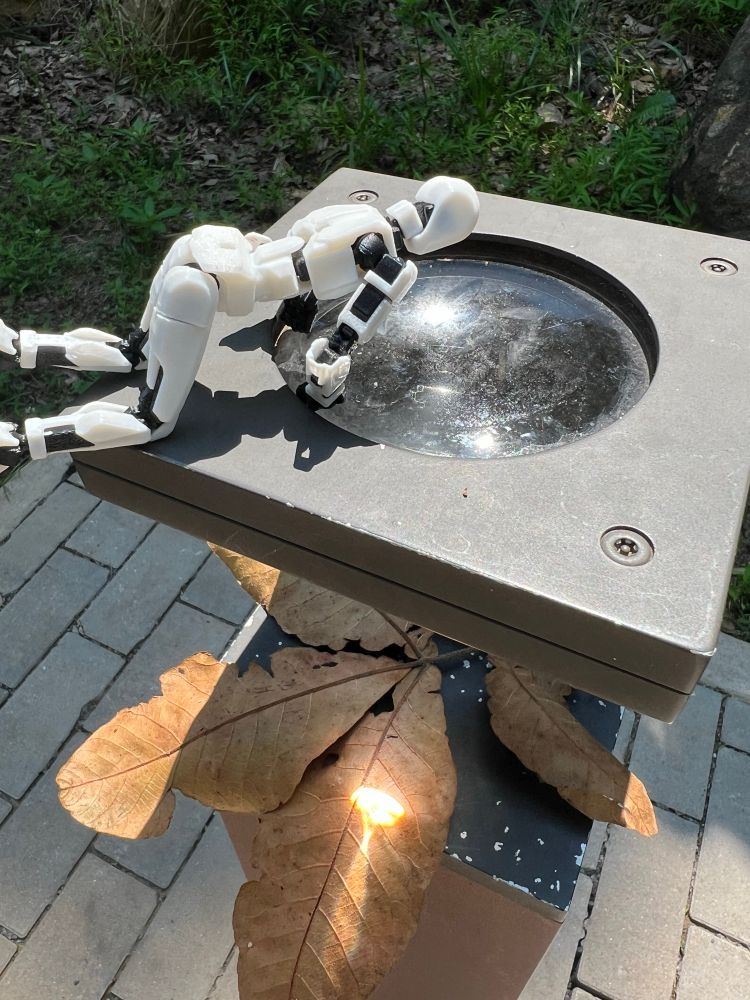 dummy 13 robot looking into a magnifying glass at a leaf