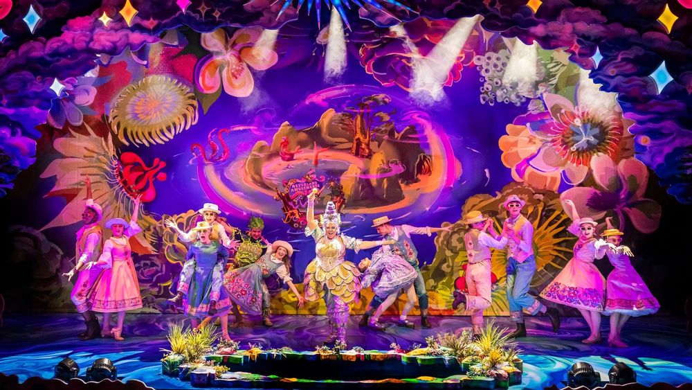 Panto cast members Sasha Latoya, Shelby Speed, David Breeds, Alexandra Barredo and Nick Brittain dance in front of a Neverland cloth with the panto chorus.