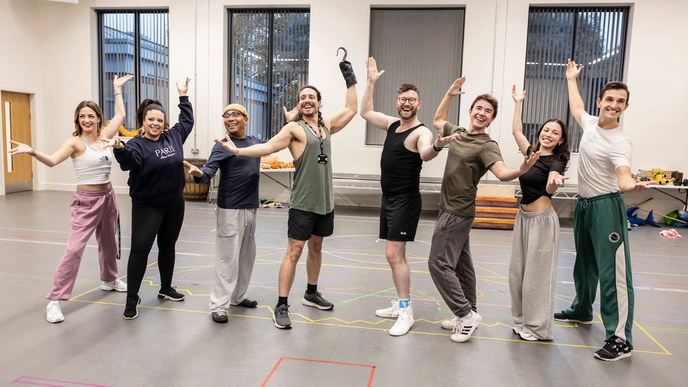 The cast of The New Adventures of Peter Pan posing joyfully in a line with their arms in the air.