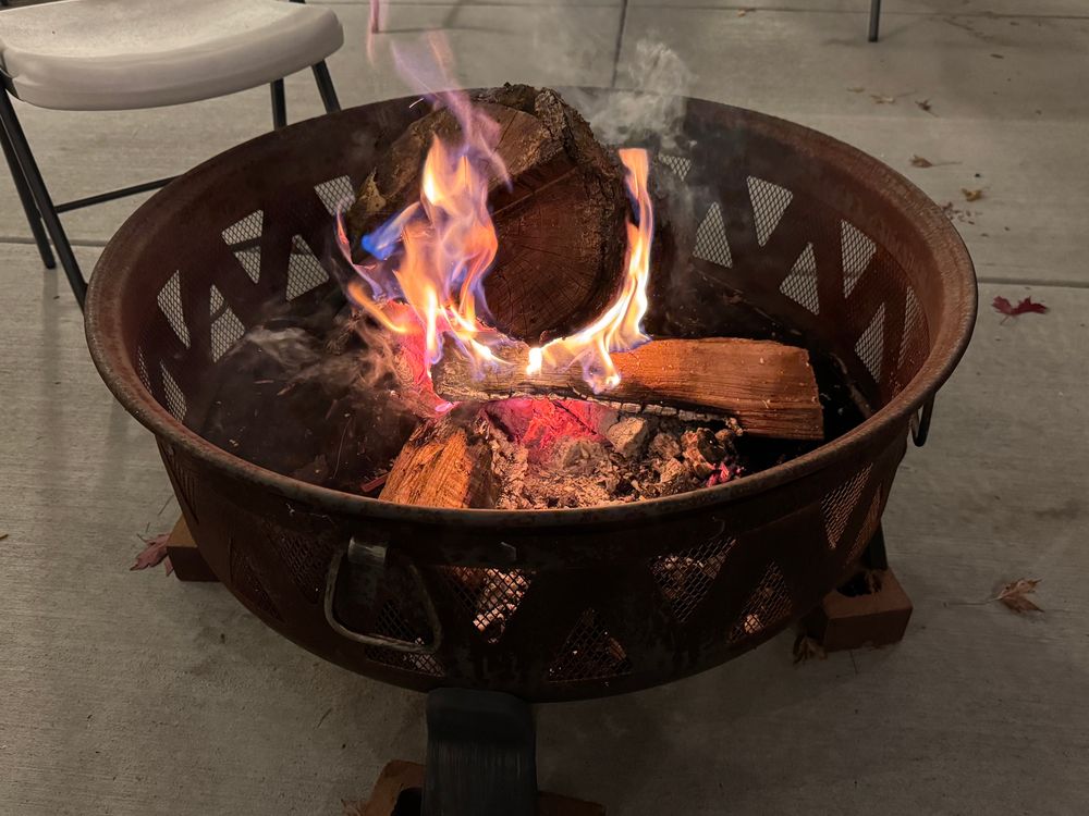 A small log fire in a steel pit, burning quite nicely