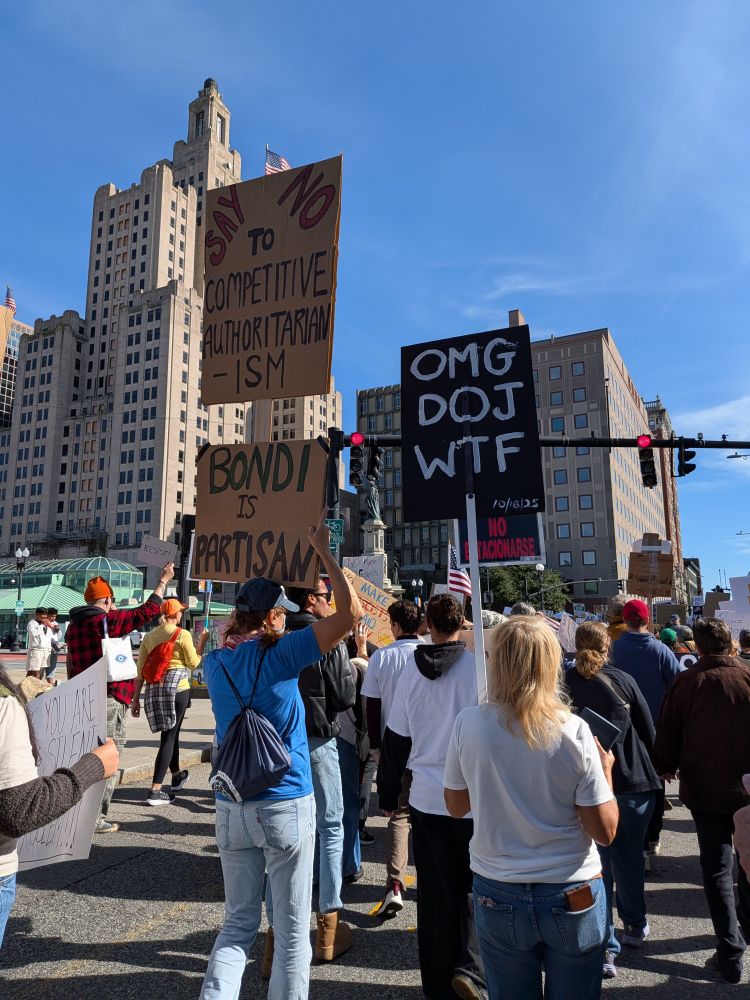 People marching in the No Kings protest in Providence RI. One sign says "OMG DOJ WTF"