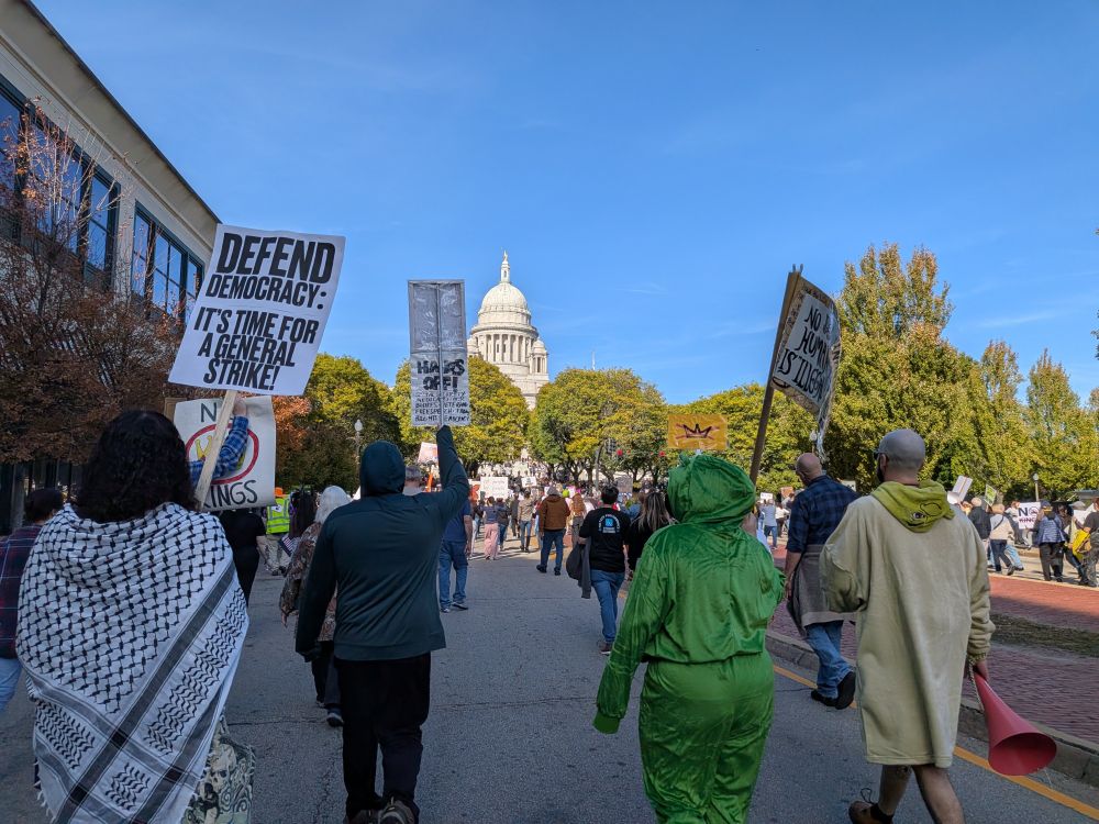 A line of people holding signs on the street leading up to the state house in Providence RI