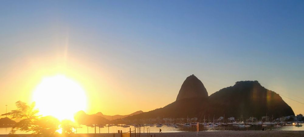 Sol nascendo em um céu azul atrás do morro do Pão de Açúcar 