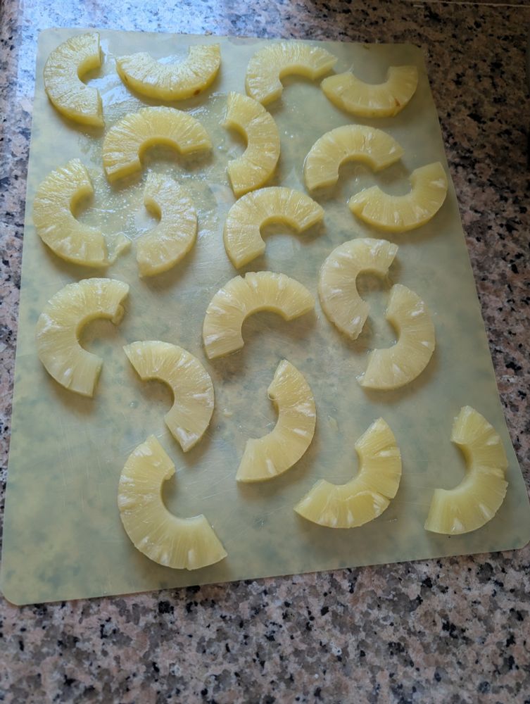 Pineapple rings sliced in half, set on a cutting board to dry