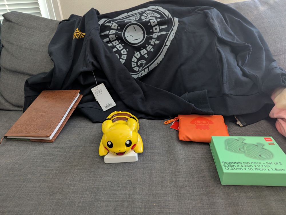 Store haul, including: 
Zelda hoodie with TotK traveler's shield design
Graph paper notebook with leather Hyrule map cover 
Splatoon zip-up tote
Animal Crossing "item" leaf ice packs
Butter dish with removable Pikachu lid